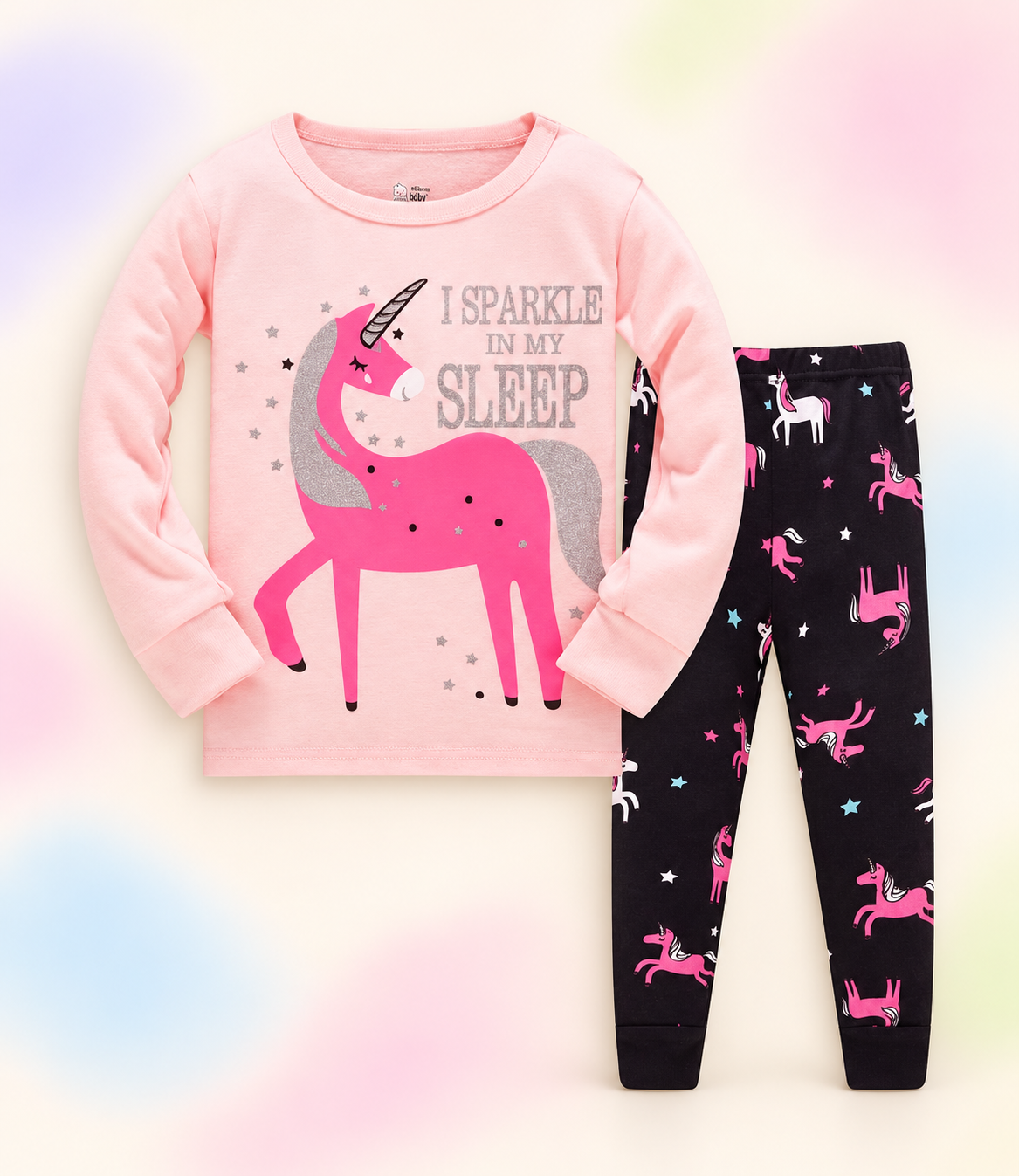 Pink unicorn pajama set with black or teal printed pants on a soft pastel branded studio background.